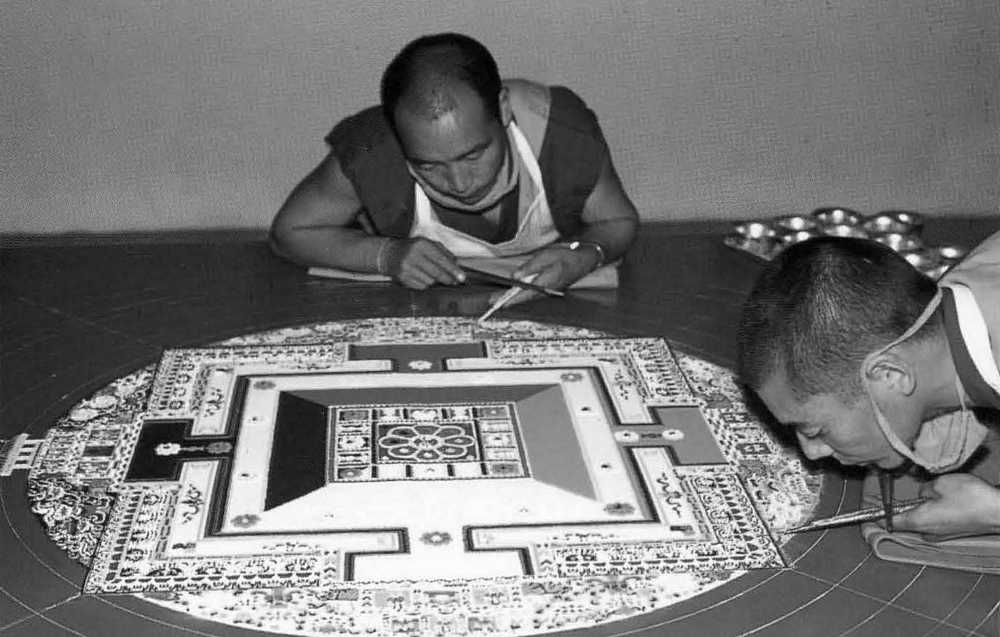 Monks carefully construing a mandala, mystical diagram, with colored sand